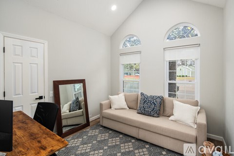 A living room with a couch, a chair, a coffee table, and a mirror.