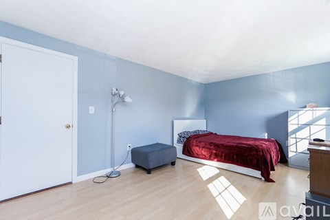 A bedroom with a red bedspread and a white bed.