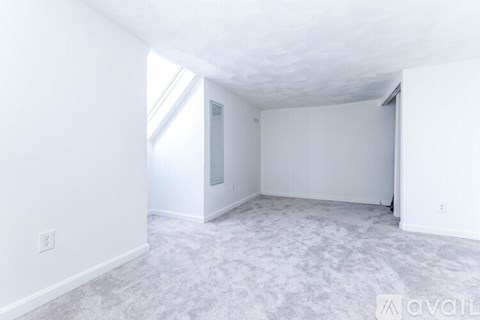 A spacious empty room with a carpeted floor and white walls.