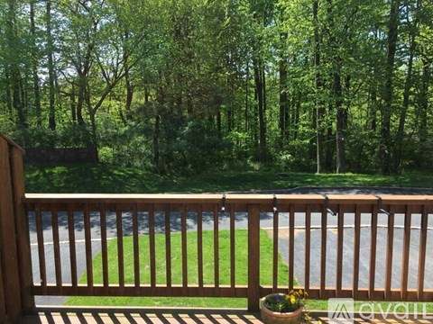 A wooden deck with a view of a winding road and trees.