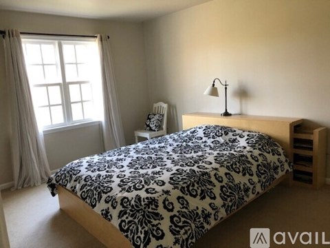 A bedroom with a bed, nightstand, and window.