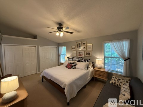 A bedroom with a bed, a ceiling fan, and a window with curtains.