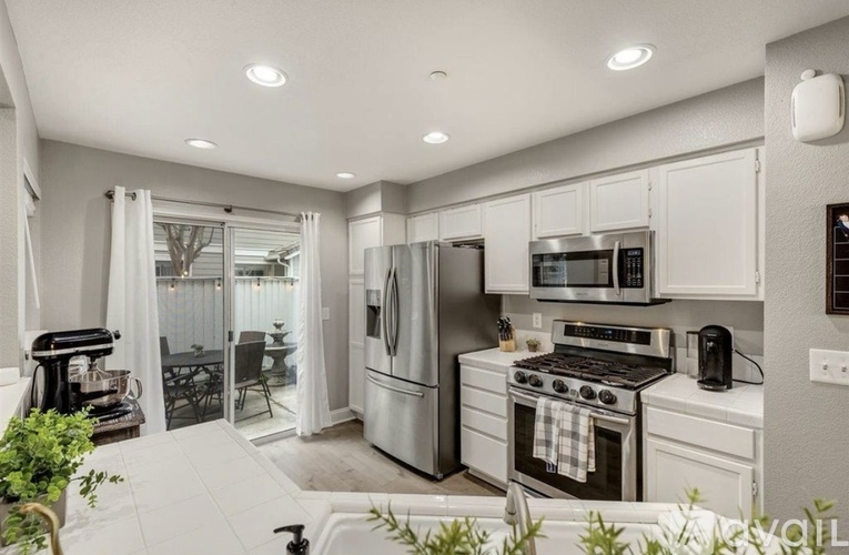 A modern kitchen with stainless steel appliances and white cabinetry.