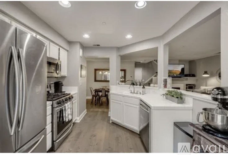 A modern kitchen with a stainless steel refrigerator and a dining area with a table and chairs.