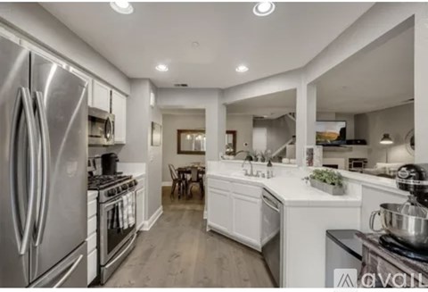 A modern kitchen with a stainless steel refrigerator and a dining area with a table and chairs.