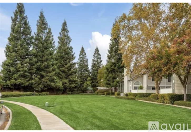 A house is for sale in a neighborhood with a green lawn and trees.
