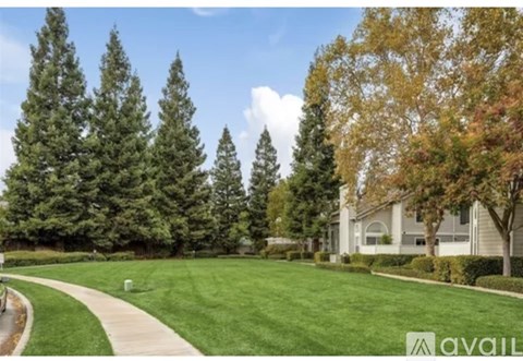 A house is for sale in a neighborhood with a green lawn and trees.