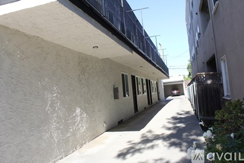 A narrow alley with a white wall on the left and a building on the right.