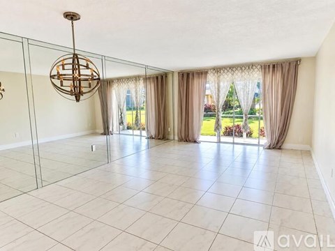 A spacious room with a glass wall and a chandelier.