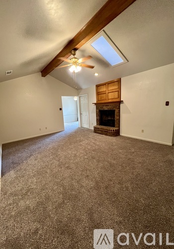 A spacious room with a fireplace and a ceiling fan.
