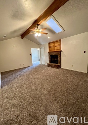 A spacious room with a fireplace and a ceiling fan.