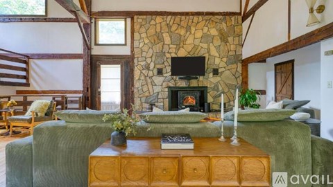A living room with a stone fireplace and a television above it.