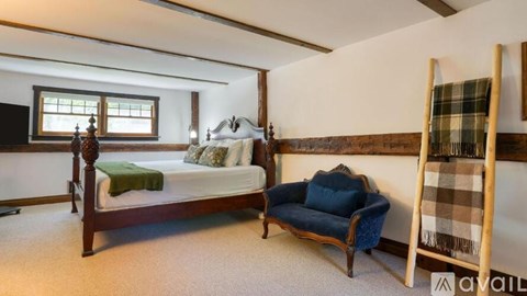 A bedroom with a bed, a chair, and a window.