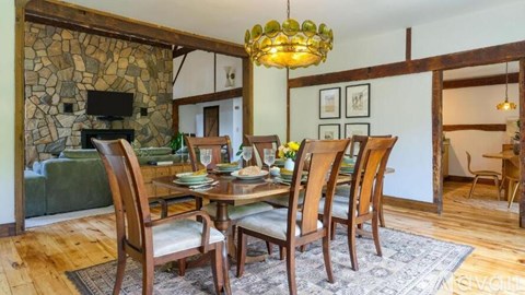 A dining room with a stone wall and a chandelier.