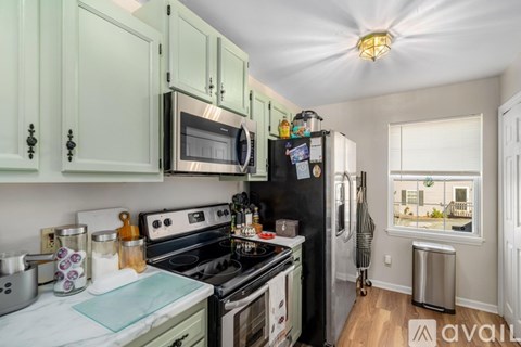 A kitchen with green cabinets and a black refrigerator.