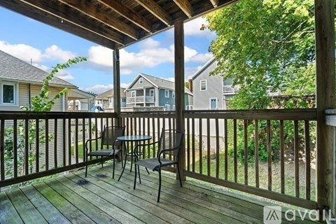 A wooden deck with a table and chairs overlooking a grassy area.