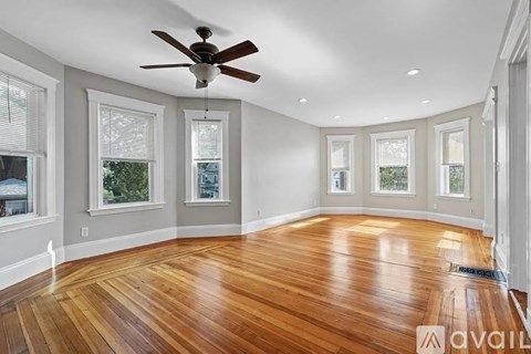A spacious room with wooden flooring and a ceiling fan.