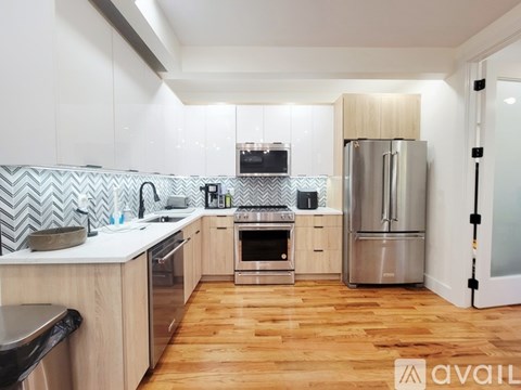 A modern kitchen with wooden floors and stainless steel appliances.