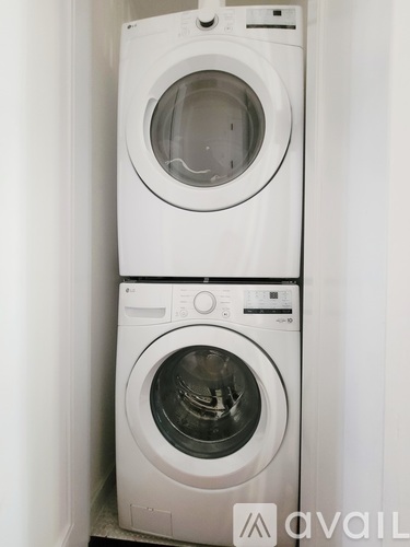 Two white front loading washing machines stacked on top of each other.