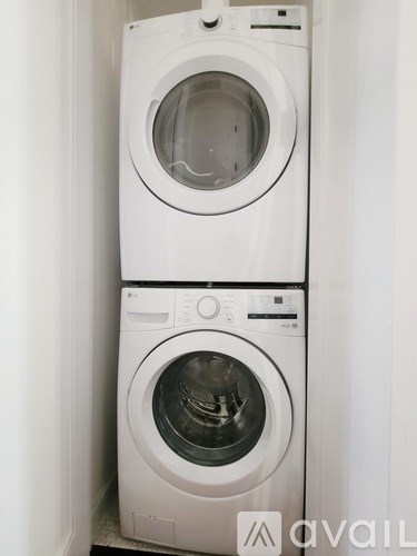 Two white front loading washing machines stacked on top of each other.
