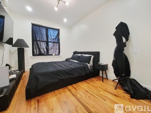 A bedroom with a bed, a desk with a lamp, and a window with curtains.