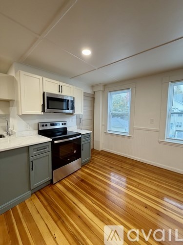 A kitchen with wooden floors and a stove top oven.