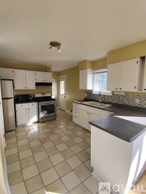 A kitchen with white cabinets and a black countertop.