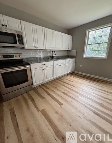 A kitchen with wooden floors and white cabinets.