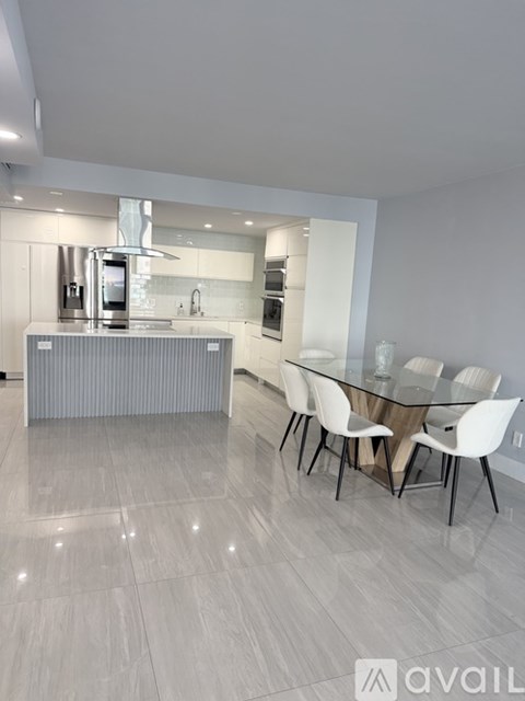 A modern kitchen with a glass table and white chairs.