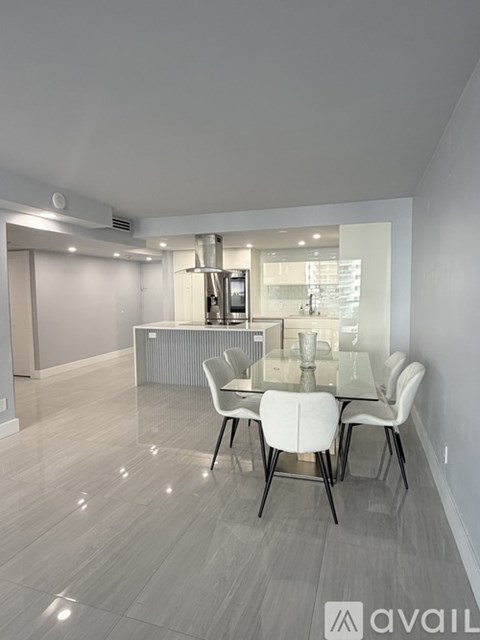 A modern dining room with a glass table and white chairs.