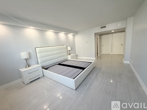 A bedroom with a large bed, nightstand, and lamp.