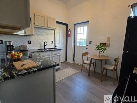 A kitchen with a marble countertop and a dining table with chairs.