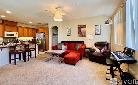 A living room with a red couch and a kitchen area in the background.
