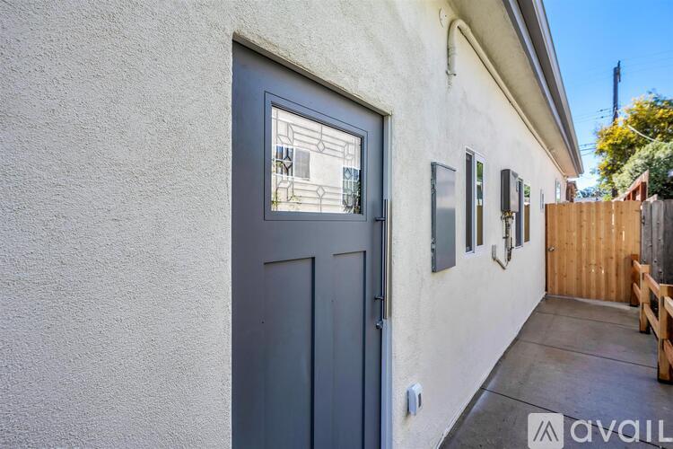 A grey door with a glass window is on a white wall.