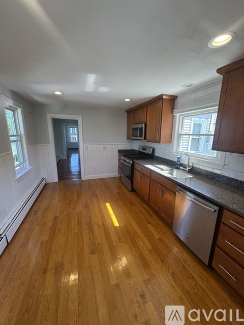 A kitchen with wooden floors and a stainless steel dishwasher.
