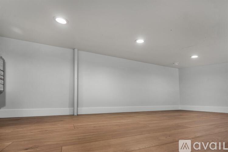A spacious room with wooden flooring and white walls.