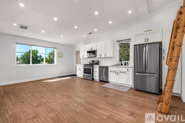 A kitchen with white cabinets and a wooden floor.