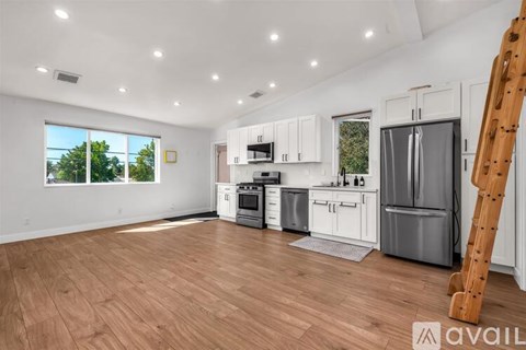 A kitchen with white cabinets and a wooden floor.
