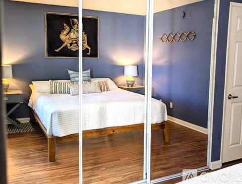 A bedroom with a bed, two lamps, and a painting on the wall.