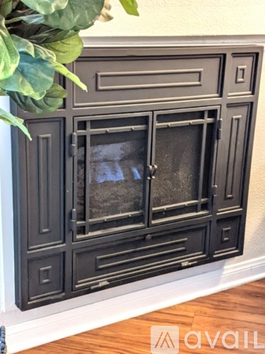 A black cabinet with glass doors and drawers is mounted on a wall.