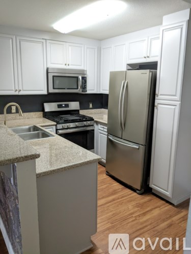 A kitchen with a stainless steel refrigerator and white cabinets.