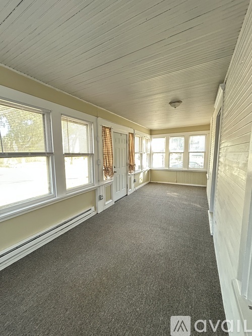 A room with a carpeted floor and a window with curtains.