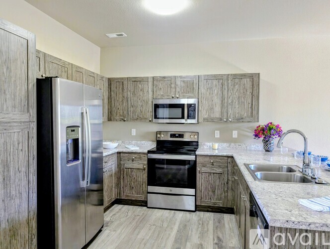 A kitchen with a stainless steel refrigerator, microwave, oven, and sink.