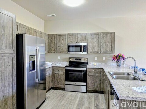 A kitchen with a stainless steel refrigerator, microwave, oven, and sink.