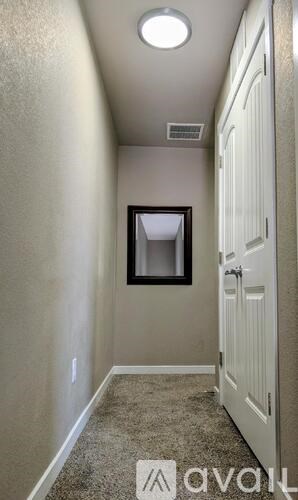 A hallway with a door on the right and a window in the middle of the wall.