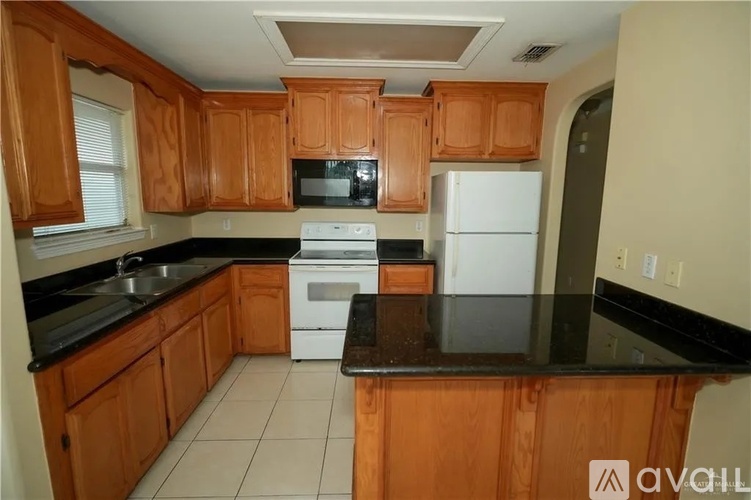 A kitchen with wooden cabinets and black countertops.