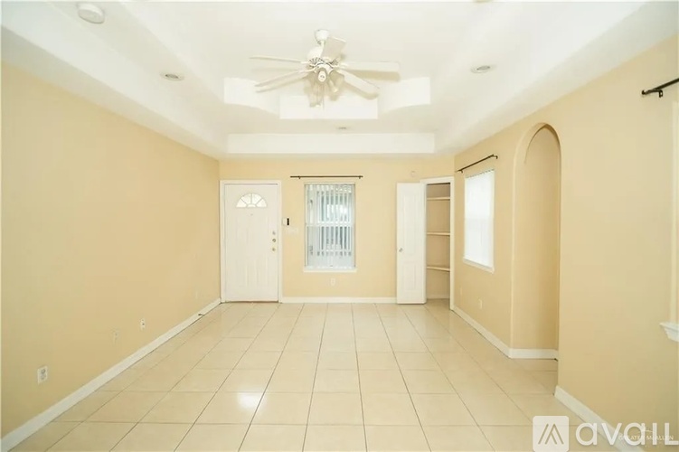 A spacious room with a ceiling fan and tiled flooring.