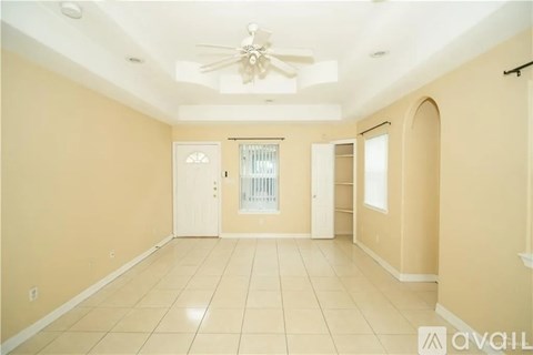 A spacious room with a ceiling fan and tiled flooring.