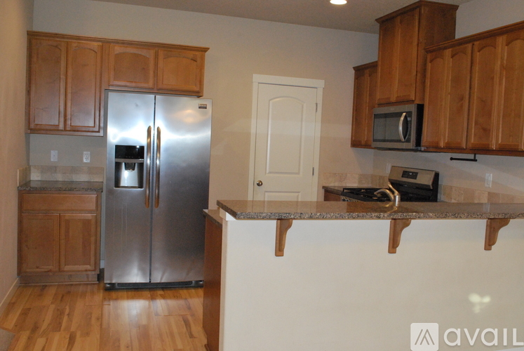 A kitchen with wooden cabinets and a stainless steel refrigerator.