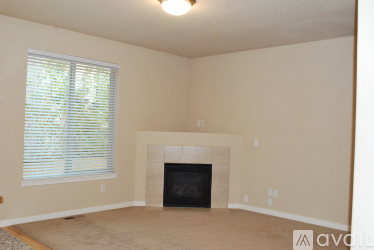 A living room with a fireplace and a window with blinds.
